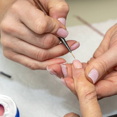 Güzellik salonunda çivi bakım prosedürü. Kadın eli ve manikür aletleri, güzellik salonunda manikür yapma süreci. Spa vücut bakımı kavramı. Tırnak etlerini kesen yetenekli bir manikürcünün eldivenli elleri.