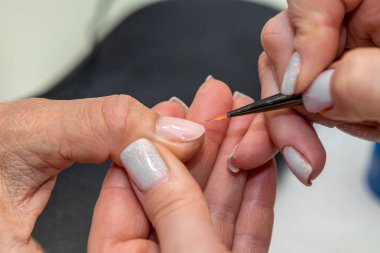 Güzellik salonunda çivi bakım prosedürü. Kadın eli ve manikür aletleri, güzellik salonunda manikür yapma süreci. Spa vücut bakımı kavramı. Tırnak etlerini kesen yetenekli bir manikürcünün eldivenli elleri.