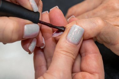 Güzellik salonunda çivi bakım prosedürü. Kadın eli ve manikür aletleri, güzellik salonunda manikür yapma süreci. Spa vücut bakımı kavramı. Tırnak etlerini kesen yetenekli bir manikürcünün eldivenli elleri.