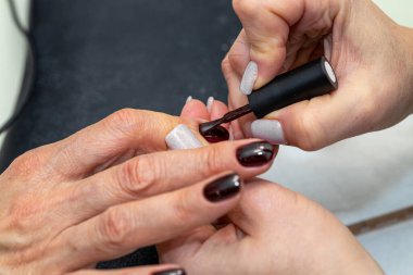 Güzellik salonunda çivi bakım prosedürü. Kadın eli ve manikür aletleri, güzellik salonunda manikür yapma süreci. Spa vücut bakımı kavramı. Tırnak etlerini kesen yetenekli bir manikürcünün eldivenli elleri.