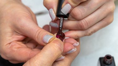 Güzellik salonunda çivi bakım prosedürü. Kadın eli ve manikür aletleri, güzellik salonunda manikür yapma süreci. Spa vücut bakımı kavramı. Tırnak etlerini kesen yetenekli bir manikürcünün eldivenli elleri.