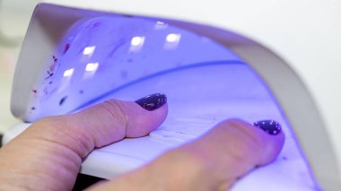 Güzellik salonunda çivi bakım prosedürü. Kadın eli ve manikür aletleri, güzellik salonunda manikür yapma süreci. Spa vücut bakımı kavramı. Tırnak etlerini kesen yetenekli bir manikürcünün eldivenli elleri.