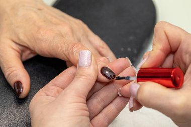 Güzellik salonunda çivi bakım prosedürü. Kadın eli ve manikür aletleri, güzellik salonunda manikür yapma süreci. Spa vücut bakımı kavramı. Tırnak etlerini kesen yetenekli bir manikürcünün eldivenli elleri.