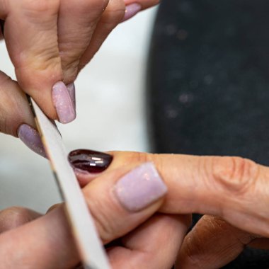 Güzellik salonunda çivi bakım prosedürü. Kadın eli ve manikür aletleri, güzellik salonunda manikür yapma süreci. Spa vücut bakımı kavramı. Tırnak etlerini kesen yetenekli bir manikürcünün eldivenli elleri.