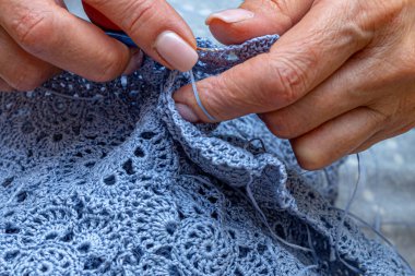 Yün ipliği kullanarak telli el yapımı giysiler ören tanınmamış bir kadının ellerine yakın durun. Boş zaman etkinliği kavramı. İplikten örgü örmek..