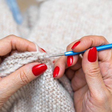 Yün ipliği kullanarak telli el yapımı giysiler ören tanınmamış bir kadının ellerine yakın durun. Boş zaman etkinliği kavramı. İplikten örgü örmek..