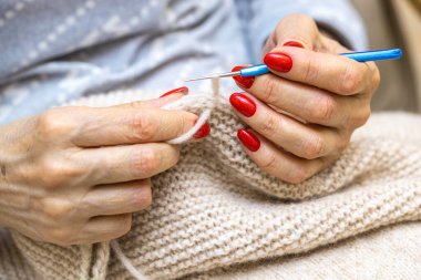 Yün ipliği kullanarak telli el yapımı giysiler ören tanınmamış bir kadının ellerine yakın durun. Boş zaman etkinliği kavramı. İplikten örgü örmek..