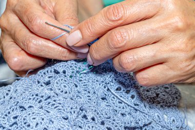 Yün ipliği kullanarak telli el yapımı giysiler ören tanınmamış bir kadının ellerine yakın durun. Boş zaman etkinliği kavramı. İplikten örgü örmek..