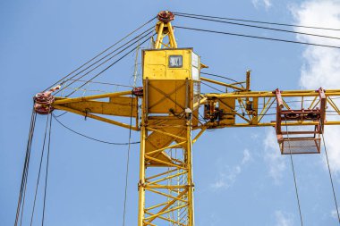 İnşaat halindeki yüksek bina, iskeleli vinç, bir inşaat alanında Freestanding kulesi. Mavi gökyüzüne karşı inşaat alanı çalışması.