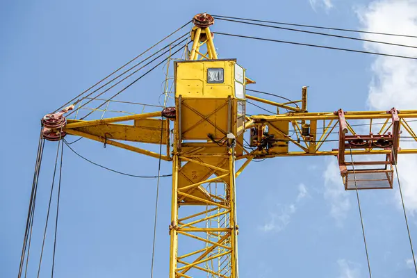 İnşaat halindeki yüksek bina, iskeleli vinç, bir inşaat alanında Freestanding kulesi. Mavi gökyüzüne karşı inşaat alanı çalışması.