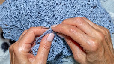 Yün ipliği kullanarak telli el yapımı giysiler ören tanınmamış bir kadının ellerine yakın durun. Boş zaman etkinliği kavramı. İplikten örgü örmek..