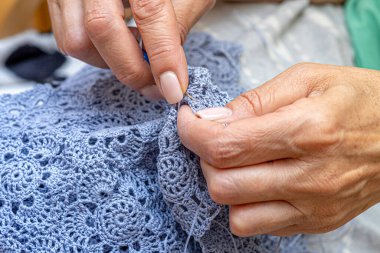 Yün ipliği kullanarak telli el yapımı giysiler ören tanınmamış bir kadının ellerine yakın durun. Boş zaman etkinliği kavramı. İplikten örgü örmek..