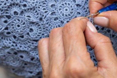 Yün ipliği kullanarak telli el yapımı giysiler ören tanınmamış bir kadının ellerine yakın durun. Boş zaman etkinliği kavramı. İplikten örgü örmek..