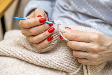 Yün ipliği kullanarak telli el yapımı giysiler ören tanınmamış bir kadının ellerine yakın durun. Boş zaman etkinliği kavramı. İplikten örgü örmek..