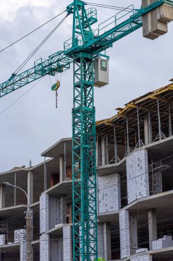 İnşaat halindeki yüksek bina, iskeleli vinç, bir inşaat alanında Freestanding kulesi. Mavi gökyüzüne karşı inşaat alanı çalışması.