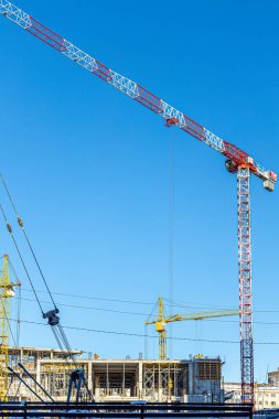 İnşaat halindeki yüksek bina, iskeleli vinç, bir inşaat alanında Freestanding kulesi. Mavi gökyüzüne karşı inşaat alanı çalışması.