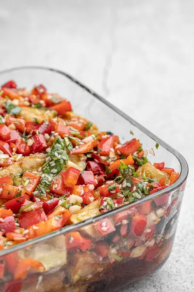 Akdeniz usulü kavrulmuş sebzeler, beyaz rustik bir masada, malzemelerle birlikte salata kasesinde. Beyaz arka planda kapari ve zeytinlerle kızartılmış sarı ve kırmızı biber salatası. Izgara sebze..