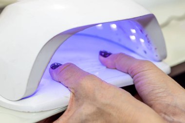 Güzellik salonunda çivi bakım prosedürü. Kadın eli ve manikür aletleri, güzellik salonunda manikür yapma süreci. Spa vücut bakımı kavramı. Tırnak etlerini kesen yetenekli bir manikürcünün eldivenli elleri.