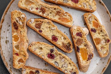 İtalyan bademli bisküvileri kırsal bir evde yapılmış çömlek kasesinde. Badem ve yaban mersiniyle süslenmiş bu iki kez pişirilmiş ikramlar aromatik ve davetkar. İdeal.