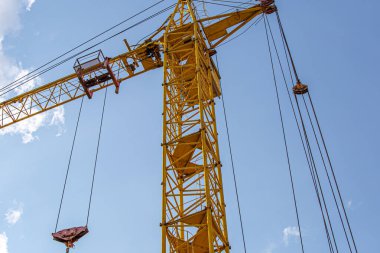 İnşaat halindeki yüksek bina, iskeleli vinç, bir inşaat alanında Freestanding kulesi. Mavi gökyüzüne karşı inşaat alanı çalışması.