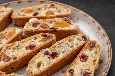 İtalyan bademli bisküvileri kırsal bir evde yapılmış çömlek kasesinde. Badem ve yaban mersiniyle süslenmiş bu iki kez pişirilmiş ikramlar aromatik ve davetkar. İdeal.