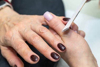 Güzellik salonunda çivi bakım prosedürü. Kadın eli ve manikür aletleri, güzellik salonunda manikür yapma süreci. Spa vücut bakımı kavramı. Tırnak etlerini kesen yetenekli bir manikürcünün eldivenli elleri.