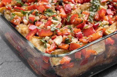 Akdeniz usulü kavrulmuş sebzeler, beyaz rustik bir masada, malzemelerle birlikte salata kasesinde. Beyaz arka planda kapari ve zeytinlerle kızartılmış sarı ve kırmızı biber salatası. Izgara sebze..