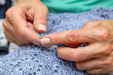 Yün ipliği kullanarak telli el yapımı giysiler ören tanınmamış bir kadının ellerine yakın durun. Boş zaman etkinliği kavramı. İplikten örgü örmek..