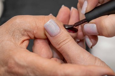 Güzellik salonunda çivi bakım prosedürü. Kadın eli ve manikür aletleri, güzellik salonunda manikür yapma süreci. Spa vücut bakımı kavramı. Tırnak etlerini kesen yetenekli bir manikürcünün eldivenli elleri.