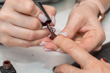 Güzellik salonunda çivi bakım prosedürü. Kadın eli ve manikür aletleri, güzellik salonunda manikür yapma süreci. Spa vücut bakımı kavramı. Tırnak etlerini kesen yetenekli bir manikürcünün eldivenli elleri.