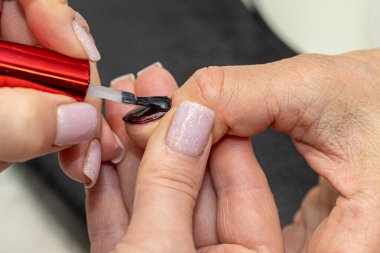 Güzellik salonunda çivi bakım prosedürü. Kadın eli ve manikür aletleri, güzellik salonunda manikür yapma süreci. Spa vücut bakımı kavramı. Tırnak etlerini kesen yetenekli bir manikürcünün eldivenli elleri.