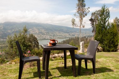 man dressed in white sitting on a chair on top of a mountain drinking a hot coffee in a cup watching the sunrise clipart