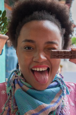 afro girl winking and holding chocolate in her hand