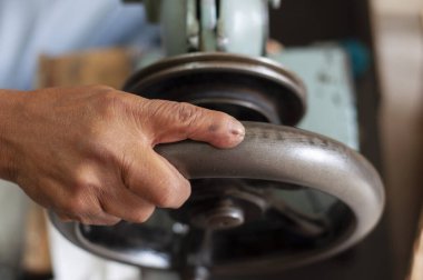 closeup of the hand of a craftsman and shoemaker moving a wheel of his machine-2