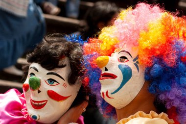 Latin Amerika 'da bir karnavalda el yapımı maskeli iki kişi. İnsanların da perukları var.