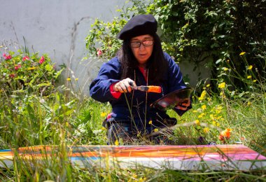 Gözlüklü emekli yaşlı kadın parkta bitkilerle çevrili bir sanat eserini boyuyor. Yüksek kalite fotoğraf