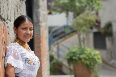 Kameraya bakıp gülümseyen ve özgür bir şekilde duvara yaslanan güçlü yerli kızın kopyası. Yüksek kalite fotoğraf