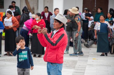Otavalo, Ekvador - 24 de junio de 2023: otavalo 'nun inti raymisinde ve otavaleno' nun kamerasına el sallayan bir çocuğun önünde yerel bir kayıt. Yüksek kalite fotoğraf