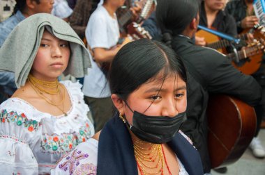 Otavalo, Ekvador - 24 de junio de 2023: Inti Raymi 'deki genç yerli insanlar, biri maskesiz ve diğeri maskesiz. Yüksek kalite fotoğraf