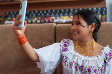 Otavalo Ekvador 'dan geleneksel elbiseli güzel bir kadın cep telefonuyla selfie çekerken gülümsüyor. Yüksek kalite fotoğraf