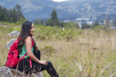 Kırmızı sırt çantalı bir kız bir dağın tepesini geziyor. Yüksek kalite fotoğraf