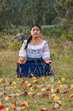 Yerli bir kadının dikey bir fotoğrafı. Doğayla iç içe geçmiş bir pozisyonda oturuyor. Yüksek kalite fotoğraf