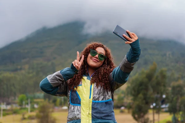 teenage rural tourism influencer from ecuador creating with had for her followers smiling and making victory sign with her fingers. High quality photo