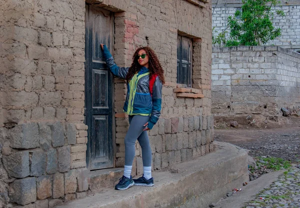 young tourist knocking on the door of a rural house on vacation in ecuador dressed in mountain clothing. High quality photo