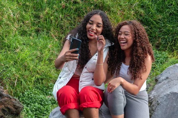 two beautiful women from latin america laughing in front of their cell phone cameras while creating content for their social networks. High quality photo