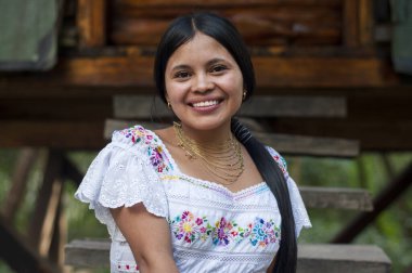 Ekvador ormanındaki evinin ahşap merdivenlerinde oturmuş kameraya gülümseyen güzel yerli bir kadın. Dünya günü. Yüksek kalite fotoğraf