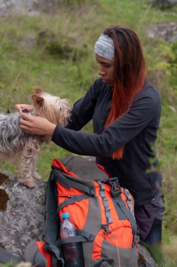Latin bir kız, sırt çantasıyla yürüyüşe çıkmadan önce köpeklerine tasma takıyor. Yüksek kalite fotoğraf