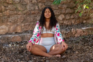 Yoga ve meditasyon yapan genç bir kadın, iç huzurunu bulup, maneviyatıyla bağlantı kurarak, zihinsel ve fiziksel refahını arttırıyor.