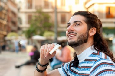 Genç adam, Valencias canlı meydanında geleneksel İspanyol nugatının keyfini çıkararak, şehrin neşeli yaşam tarzını somutlaştırıyor. Seyahat içeriği için mükemmel