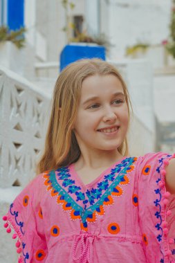 Canlı, geleneksel elbiseli neşeli genç bir kız büyüleyici doğal ortamında hoş bir selfie çeker.